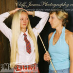 Naughty schoolgirl keeps her hands on her head before bending for a hard caning